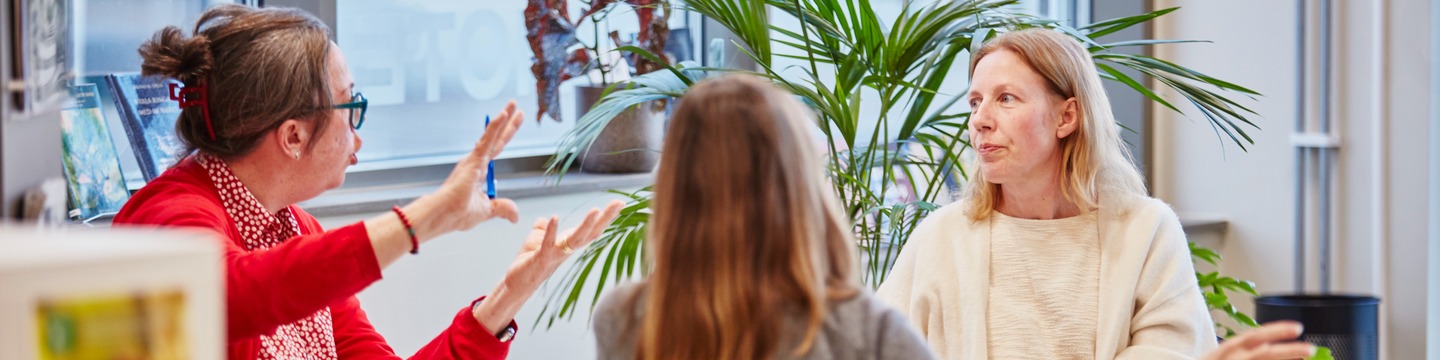 tre personer pratar runt ett bord