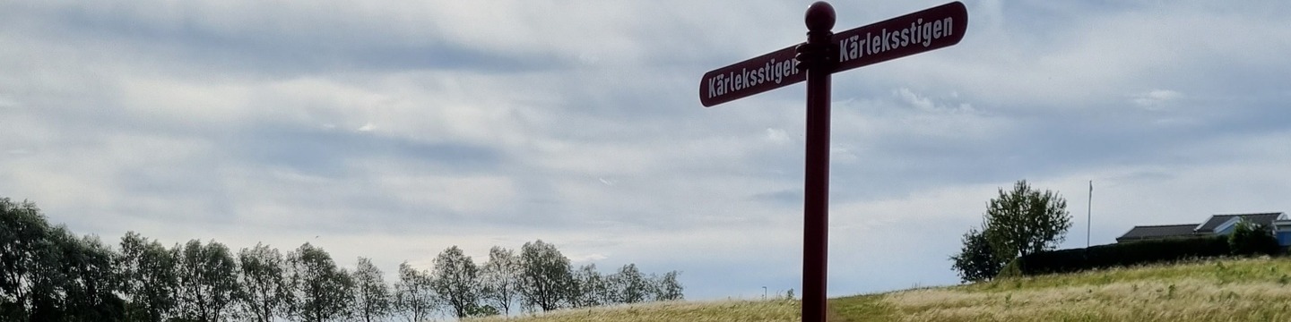 Ett fält med en skylt fär det står kärlekstigen i förgrunden